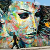 Hombre caminando frente a un mural colorido de arte callejero a gran escala en Wynwood Walls, Miami.