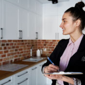 Agente inmobiliaria realizando una inspección final o "final walkthrough" en una cocina moderna con una tabla portapapeles.