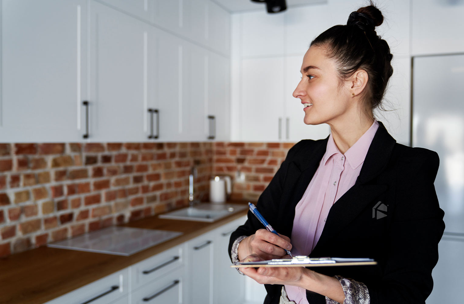 Agente inmobiliaria realizando una inspección final o "final walkthrough" en una cocina moderna con una tabla portapapeles.