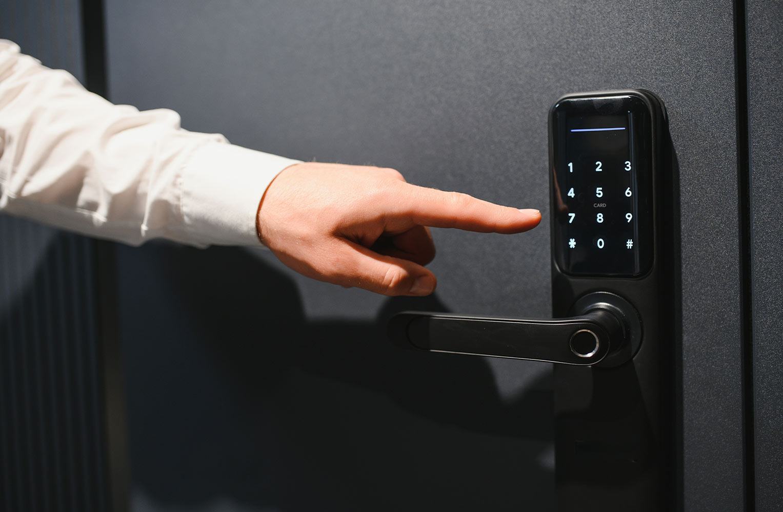 Primer plano de una mano utilizando el teclado numérico de una cerradura inteligente en una puerta moderna.