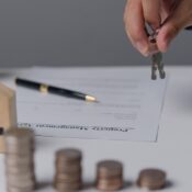 Persona entregando llaves de casa sobre un contrato de gestión de propiedades y monedas apiladas que representan los gastos de cierre en Florida.