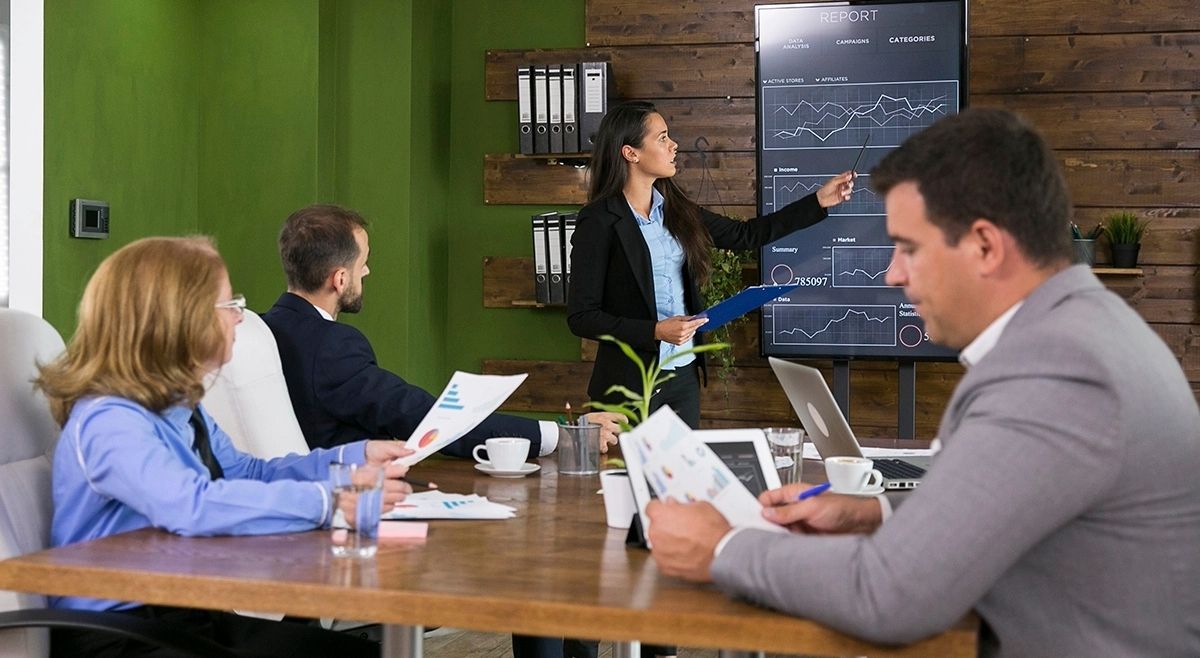 Presentación de Real Estate Syndication en Orlando para inversores extranjeros, mostrando análisis de datos, reportes de rentabilidad y proyecciones de inversión inmobiliaria colectiva en una oficina moderna.