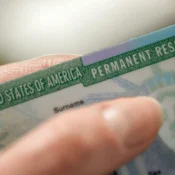 Mano sosteniendo una Green Card de residencia permanente de Estados Unidos, beneficio de la visa EB-5 para inversionistas en Florida