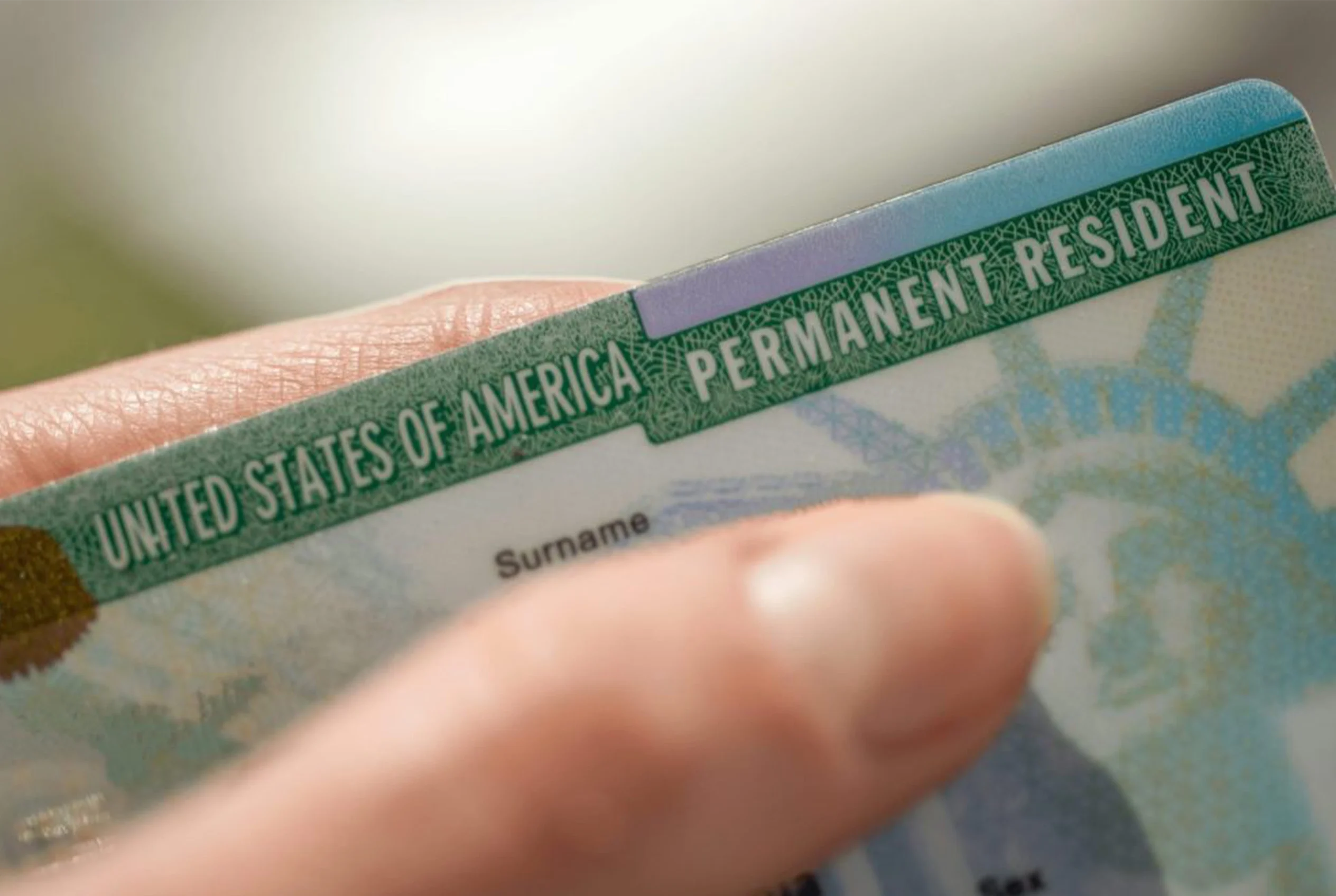 Mano sosteniendo una Green Card de residencia permanente de Estados Unidos, beneficio de la visa EB-5 para inversionistas en Florida