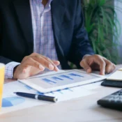 Inversionista inmobiliario analizando gráficas de rentabilidad en tablet con calculadora y reportes sobre la mesa para evaluar cap rate y ROI en Orlando