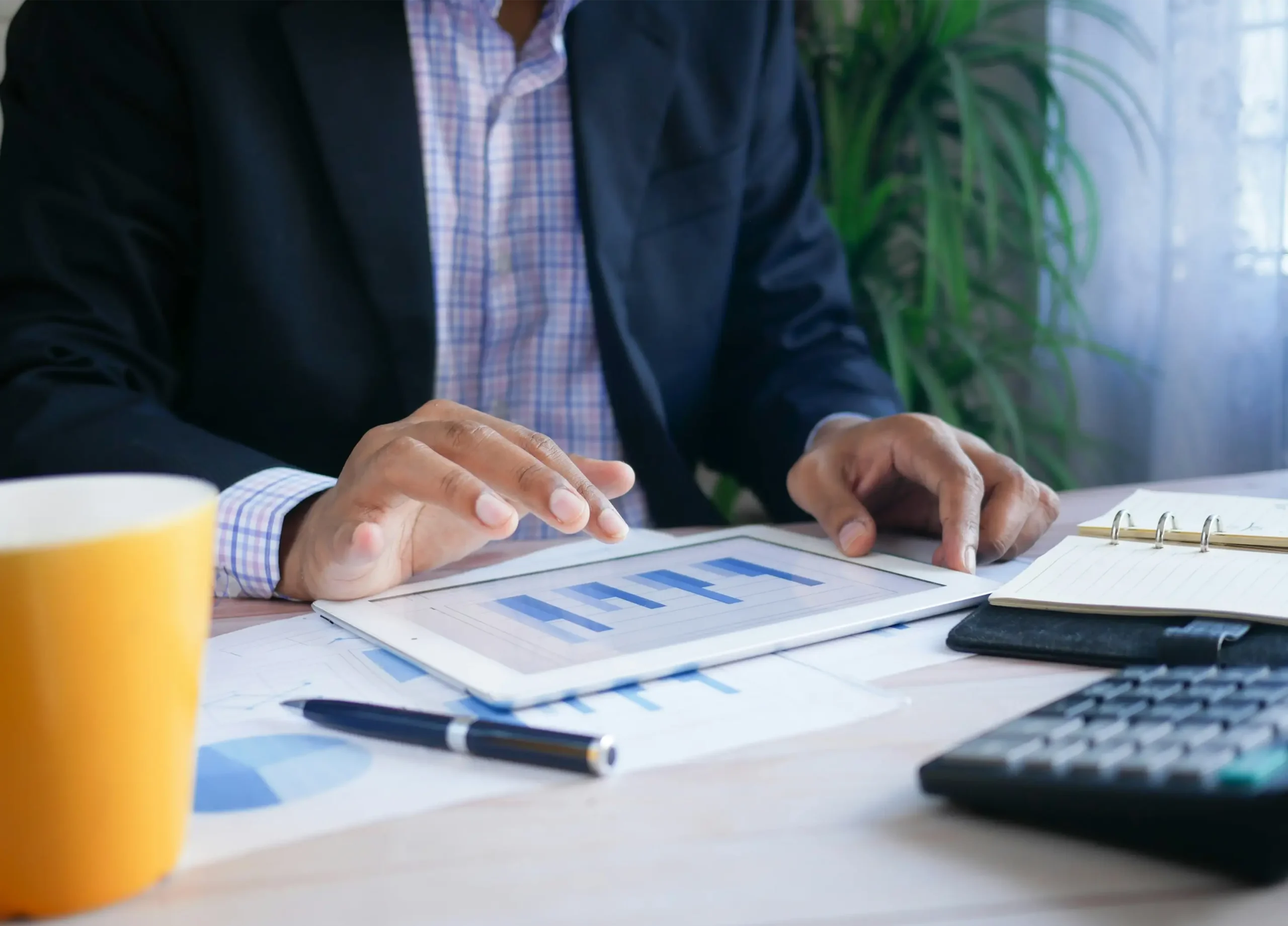 Inversionista inmobiliario analizando gráficas de rentabilidad en tablet con calculadora y reportes sobre la mesa para evaluar cap rate y ROI en Orlando