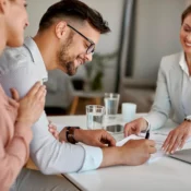Pareja compradora revisando y firmando oferta de compra con agente inmobiliaria en Florida, resultado exitoso de negociación de precio