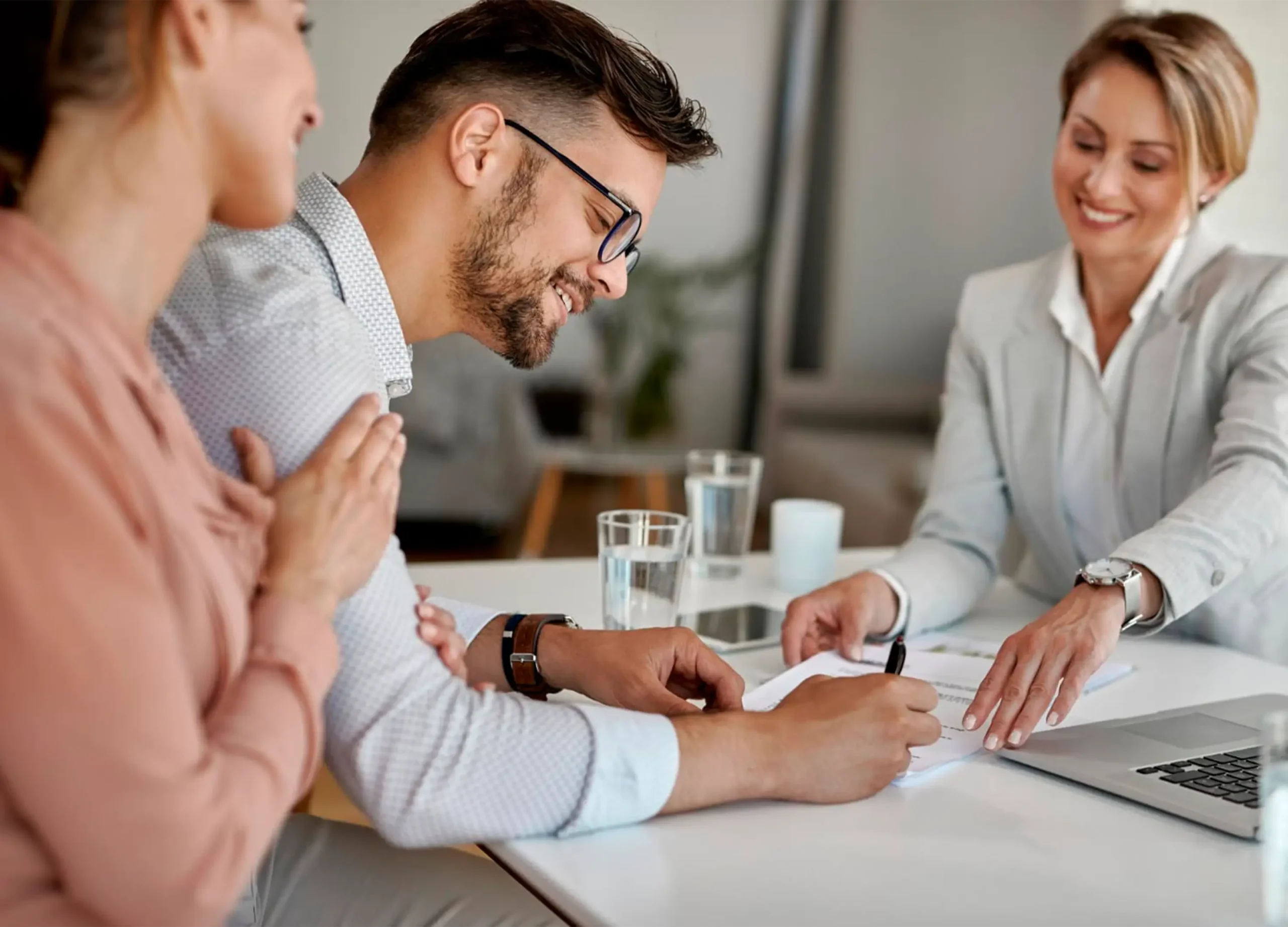 Pareja compradora revisando y firmando oferta de compra con agente inmobiliaria en Florida, resultado exitoso de negociación de precio