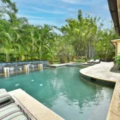 Piscina privada con cascada de piedra, jacuzzi y jardín tropical en propiedad vacacional de lujo en Orlando, Florida