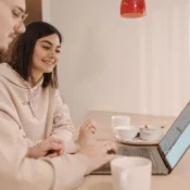 Pareja joven revisando reservas en laptop para gestionar su Airbnb en Orlando.