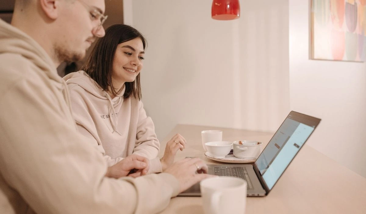 Pareja joven revisando reservas en laptop para gestionar su Airbnb en Orlando.