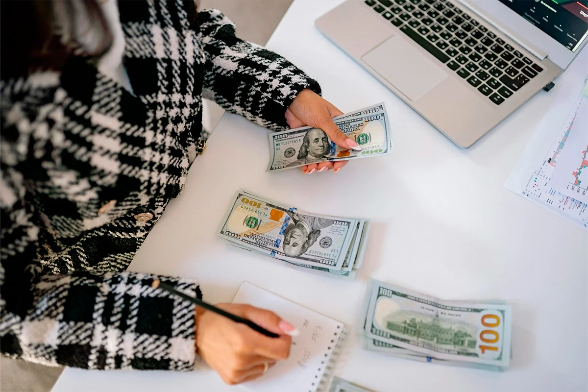 Mujer contando billetes de dólar para ahorrar el down payment de una propiedad en Florida.