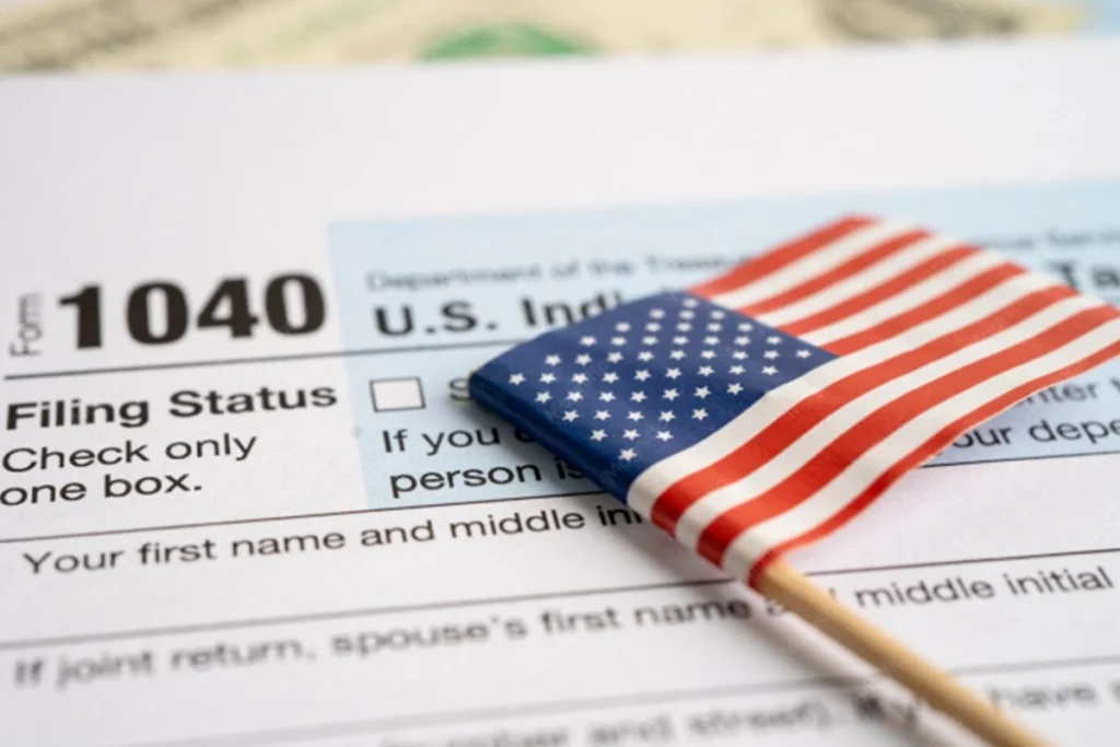US Form 1040 individual tax return with a small American flag placed on top.