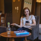 Mujer sonriente revisando su teléfono sentada en la sala de una renta vacacional en Orlando