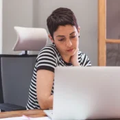 Mujer concentrada frente a laptop investigando cómo invertir en bienes raíces en Florida.