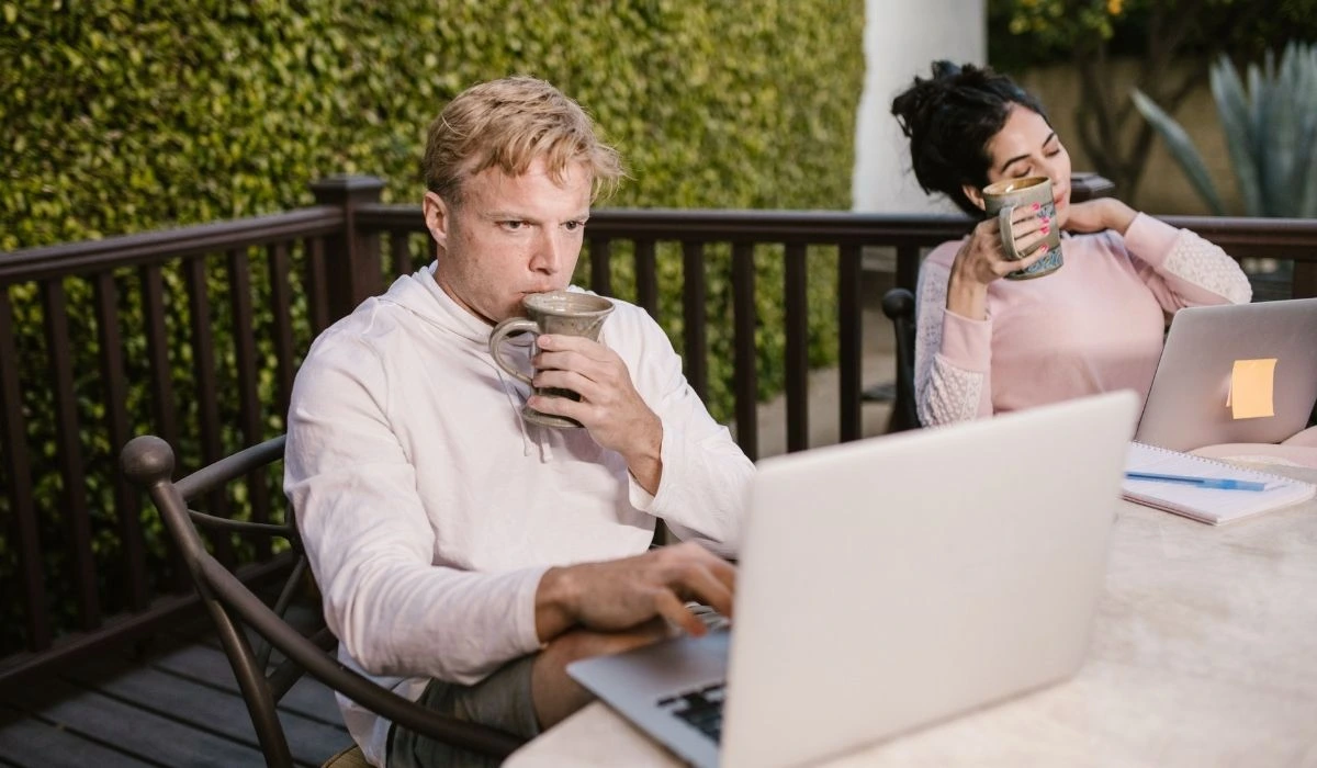 Pareja con laptops en terraza revisando rentabilidad de propiedad Airbnb Orlando