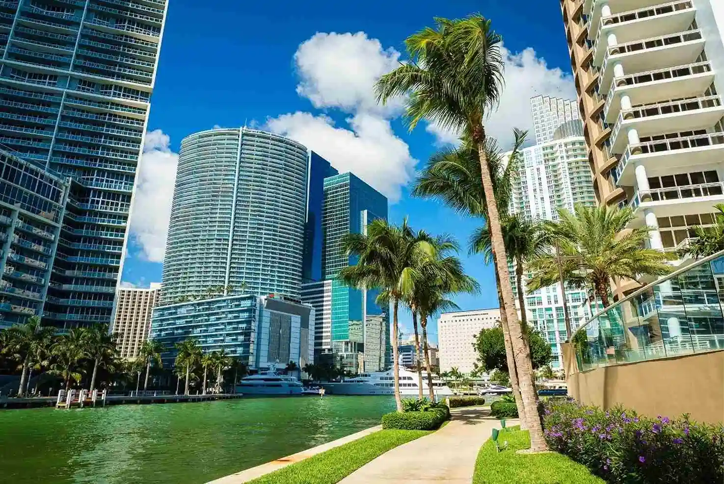 Brickell skyline in Miami with luxury buildings, a river, and palm trees.