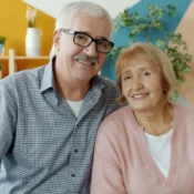 Pareja sonriente de adultos mayores disfrutando del descanso en la sala de su segunda residencia de invierno en Florida.