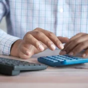 Persona haciendo cuentas con calculadora en un escritorio para calcular el costo de mantener una propiedad en Florida.